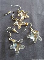 Both pairs of crystal starfish earrings laid out on fabric background