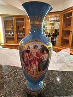 Front view showing cobalt blue glaze, gilt scrolls, and primary classical scene