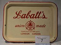 Photo of a rectangular cream-colored porcelain enamel serving tray with red border and 'Labatt's union made' logo in red lettering.