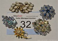 Photo showing five vintage brooches of varied colors and designs on MaxSold auction bid card
