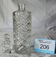 Crystal wine decanter and its stopper shown against a light background with an auction lot number card.