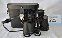 FOCAL binoculars resting beside their black carrying case with strap and metal clasp.