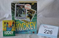 Photo of unopened O Pee Chee 1990-1991 hockey cards box with bubble gum, featuring Bill Ranford and Ray Bourque on the cover, alongside an unopened pack.