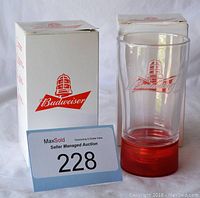 Photo showing one Budweiser red light glass with embossed logo, original packaging boxes included. Glass is clear with red light base.