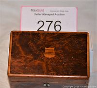 Closed music box showing finely grained wooden case with key lock.