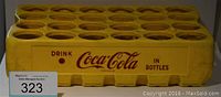 Side view of yellow Coca-Cola bottle carrying case with 24 slots and Coca-Cola red branding.