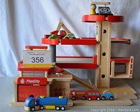 Overall view of wooden Plan City toy set showing parking structure, fire station, and vehicles lined up in front