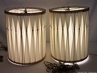 Both swag lamps illuminated showing pleated fabric and gold trim
