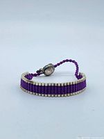 Full view of bracelet laid flat showing silver beads and purple cord