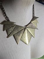 Front view showing layered triangular plates and chain