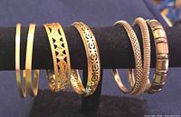 Seven assorted gold-tone bangles on display bar