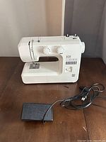 Full view of sewing machine with foot pedal and power cord