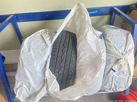 Three of four tires in Michelin bags on blue rack, one bag opened to show tread