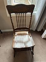 front view showing carved crest rail, spindle back, shaped seat