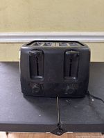 Front view showing dual slots, levers and knobs of black toaster