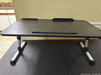 Full view of black wood/MDF laptop stand on silver/black adjustable legs