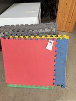 Front view of stacked multicolor EVA foam tiles showing red tile on top and interlocking edges