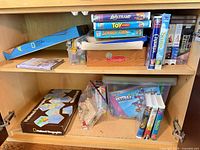 Full cabinet view showing board games, VHS stacks, loose bricks