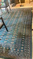 Full view of large dark green patterned area rug