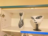 Front view of tulip vase and footed face vase on shelf
