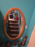 Front view of oval wood framed mirror hanging on wall