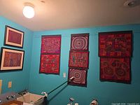 Overall view showing two framed molas and six unframed panels on wall