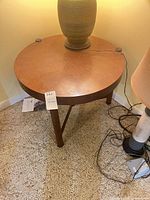 Full view of round wood table showing top, legs, surrounding items for scale