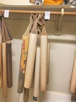 Eight rolled posters hanging from rod, mix of brown and beige sleeves