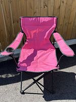 Front view of pink folding camping chair showing seat, armrests and cup holder