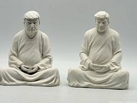 Front view of both Trump Buddha figurines side by side