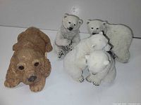 Group view showing all four figurines: Sandicast dog and three Nanouk polar bears