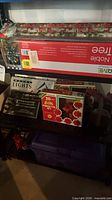 Overall shelf view showing boxed tree, light sets, poinsettia lights, wrapping paper, tote