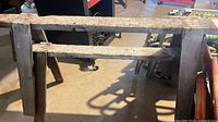 Front view of one sawhorse showing worn top beam and braces