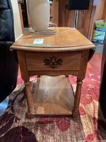 Full view of oak veneer drop-leaf side table between chairs