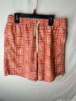 Front view of coral Rhythm swim trunks hanging