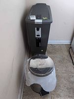 Tall dark grey Simplehuman 40 L trash can beside smaller round metal can
