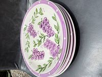 Stack of four plates, top view showing grape design