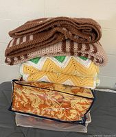 Stack of four crocheted blankets showing colors and patterns