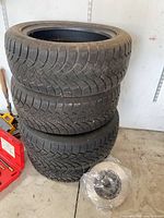 Stack of three tires with tread visible and wrapped brake rotor beside them