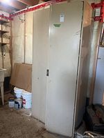 Front view of tall beige metal cabinet in basement