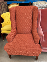 Front view of rust jacquard wingback armchair showing upholstery pattern, arms, backrest and wooden legs