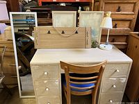 Front view of desk, chair, mirror, note board, lamp, prints, glass apple