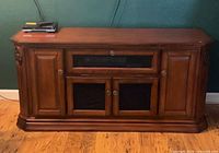 Front view of brown cherry TV stand showing overall design and glass doors