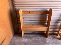Full front view of solid pine bench against metal wall