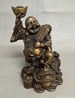 Front view showing Buddha holding ingot, frog base, fan and necklace details
