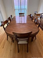 Top view of extended mahogany dining table with eight chairs shown for scale