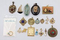 Group shot of 19 vintage pendants and charms laid out on white background