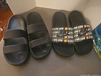 Two pairs of black slide sandals side by side on surface