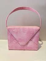 Front view of pink structured handbag showing envelope flap and handle