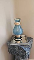 Front view of teal frosted vase on stand showing gilded bands